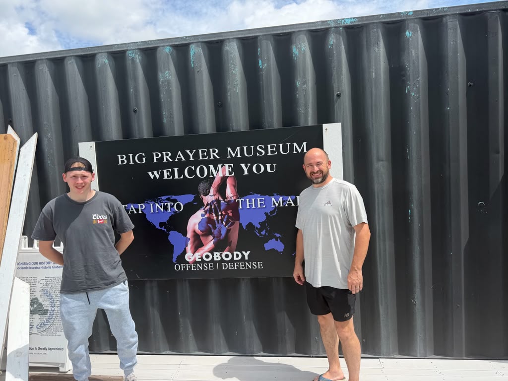 Visitors standing beside a Big Prayer Museum Tap Into the Map display