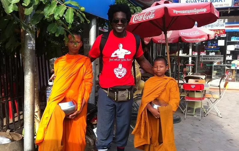 Real photograph from Cambodia showing a person standing with two young Buddhist monks
